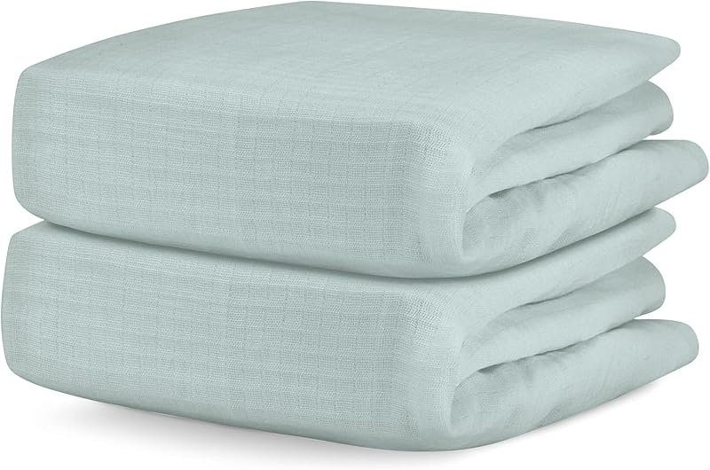 Two folded sage green organic cotton fitted crib sheets on a white background